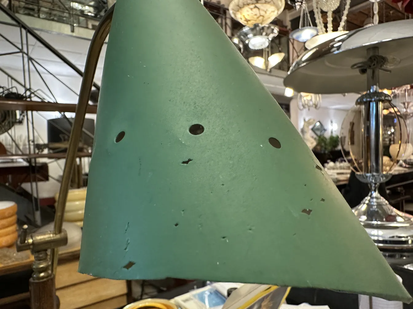 Lampada da tavolo antica verde con fori decorativi, circondata da arredi vintage.