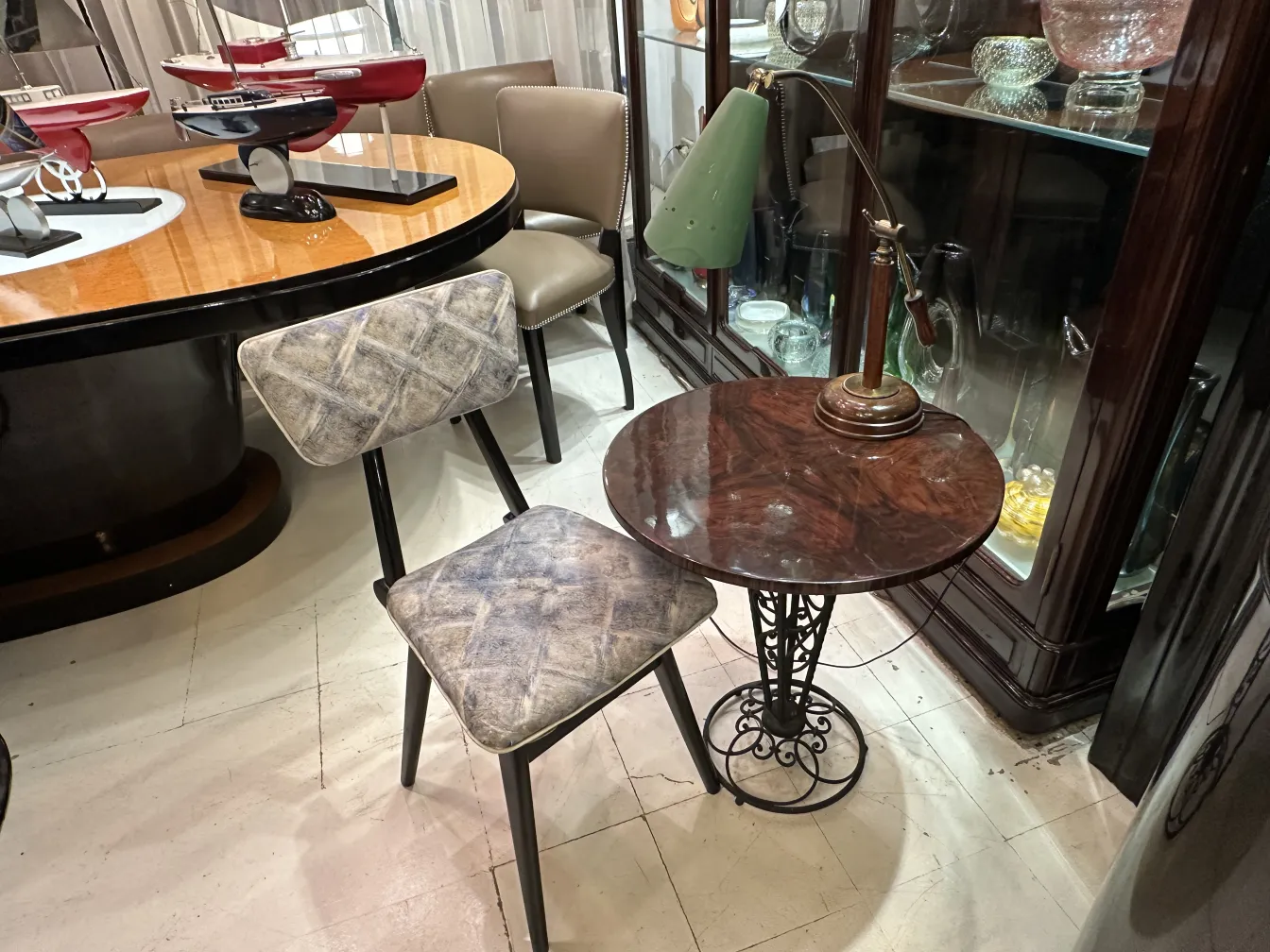 antique table lamp with green shade and brass base, surrounded by chairs and tables in a cozy setting