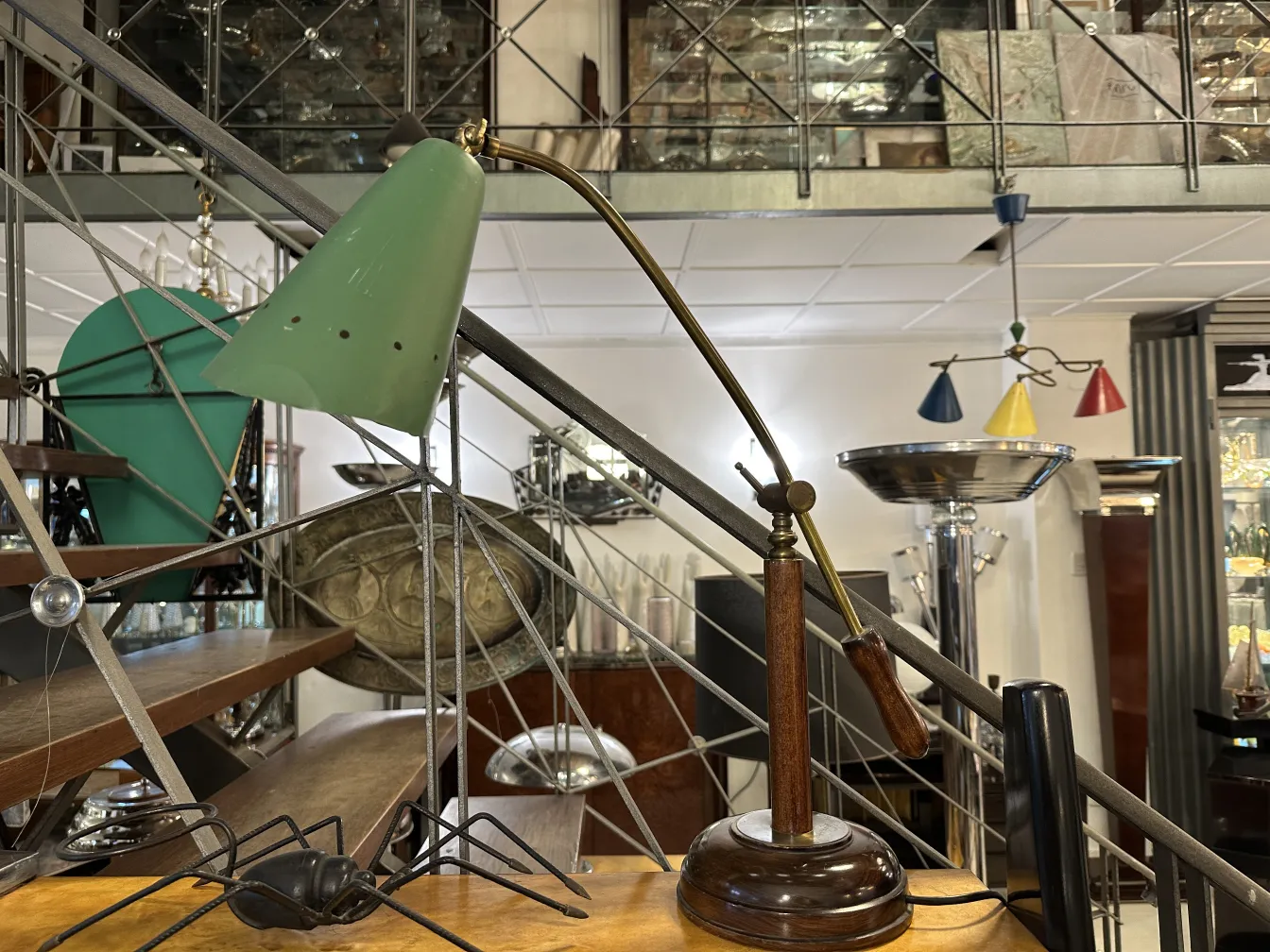 Antica lampada da tavolo verde con base in legno, in un ambiente di antiquariato.