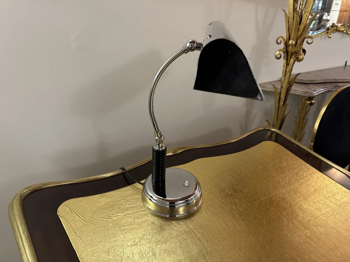 Lampe de bureau ancienne avec base polie, design élégant, ambiance sophistiquée, sur surface dorée.