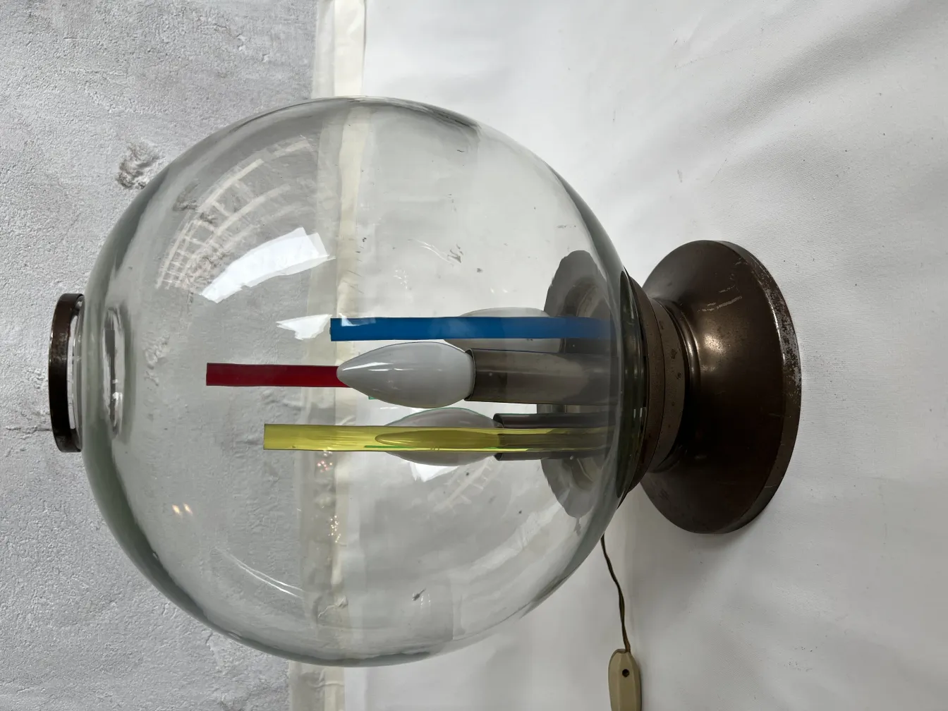 Lampada da tavolo antica di forma rotonda con elementi colorati in un contesto minimalista.