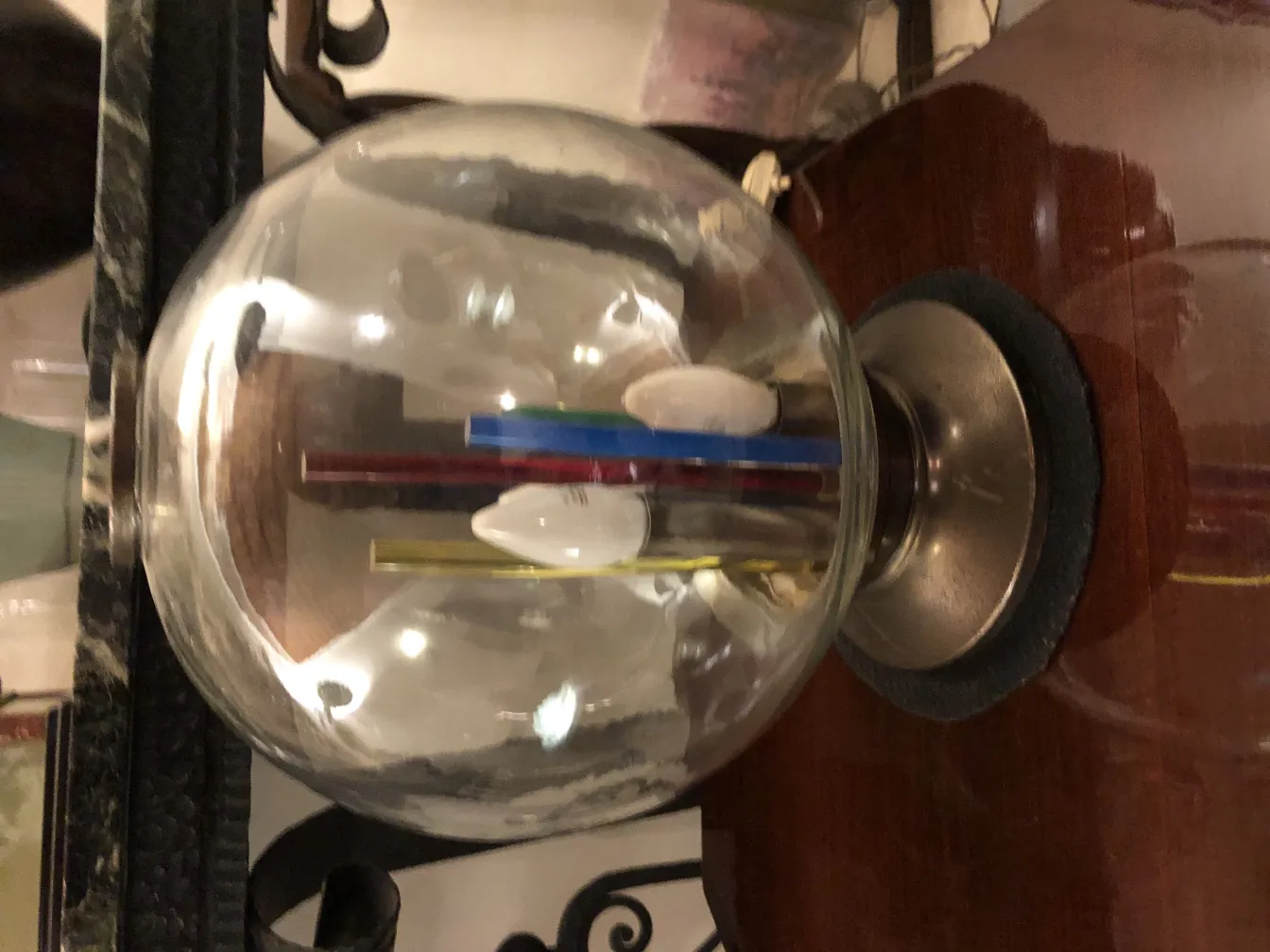 Lampada da tavolo antica con globo e tubi colorati su un tavolo in legno.