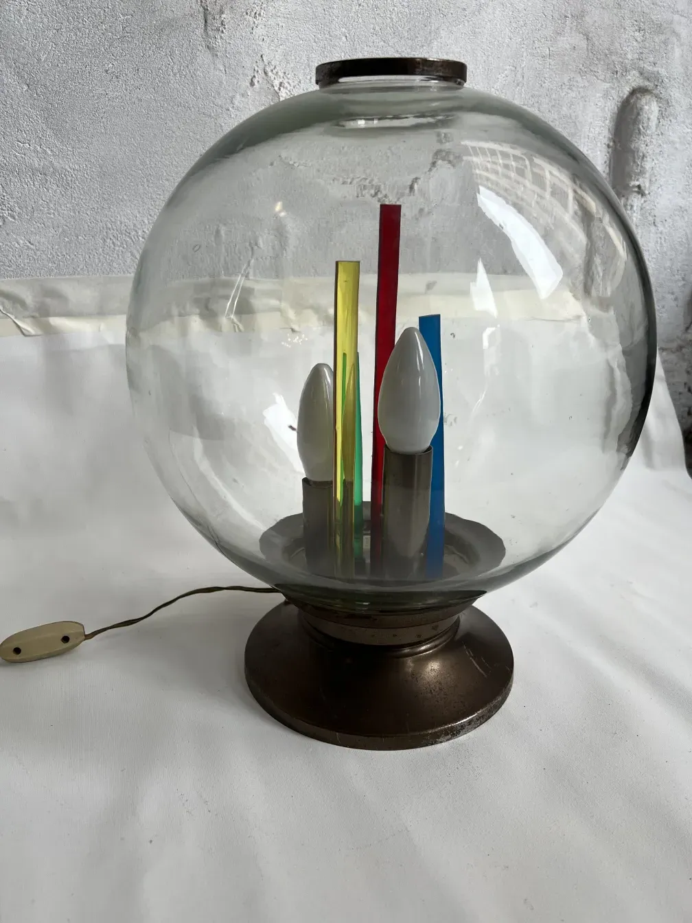 Luminária de mesa antiga com base redonda e elementos coloridos dentro.