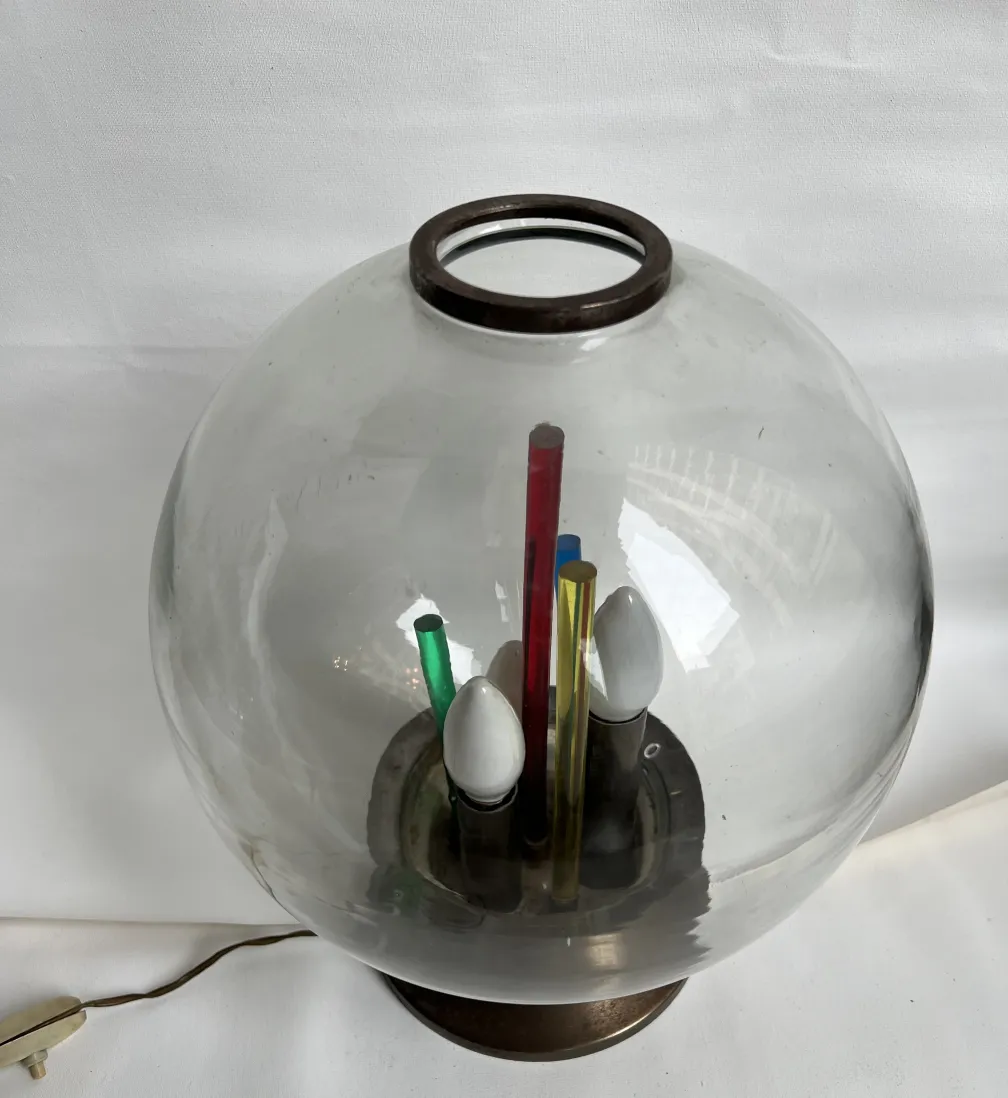 Lámpara de mesa antigua con forma esférica y luz suave, rodeada de lápices de colores. Ideal para escritorio.