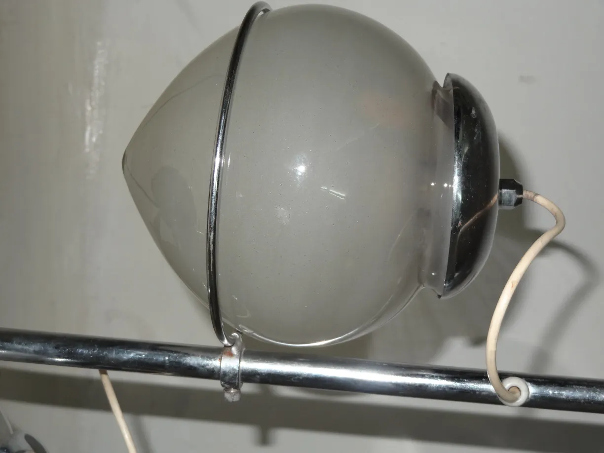 Luminária de mesa antiga com formato esférico e detalhes metálicos, ambiente minimalista.