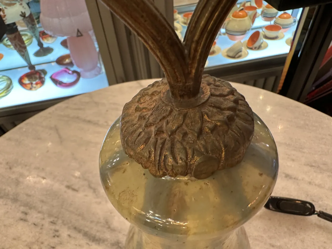 مصباح طاولة قديم بقاعدة مزخرفة، جو دافئ، ألوان فاتحة.