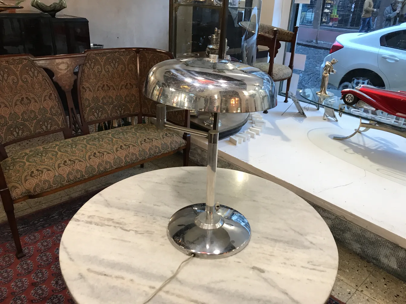 Lampada da tavolo antica con base rotonda e luce morbida, in un ambiente accogliente con un divano. Perfetta per la decorazione.