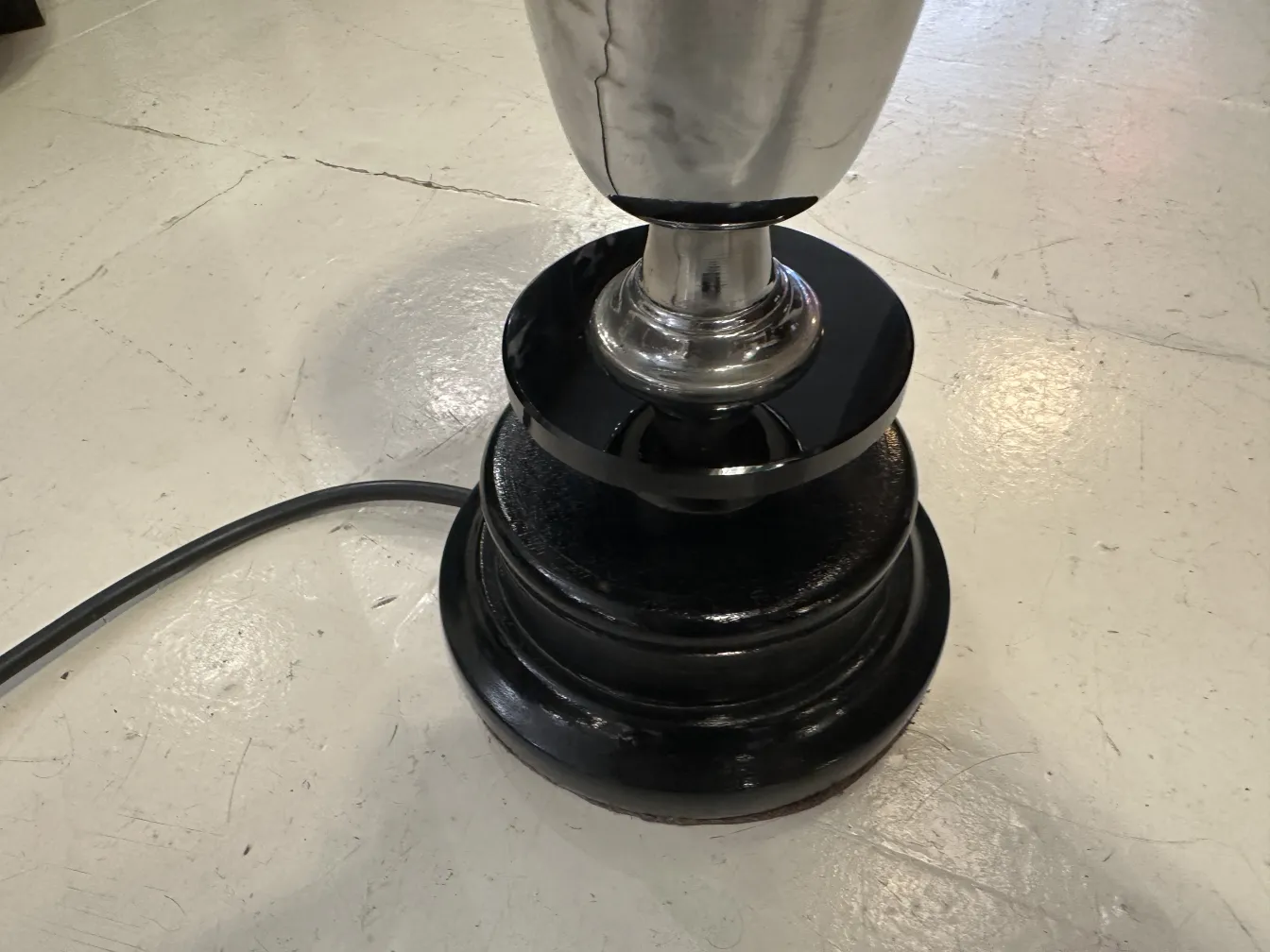 Старинная настольная лампа с круглым черным основанием, нейтральная обстановка.