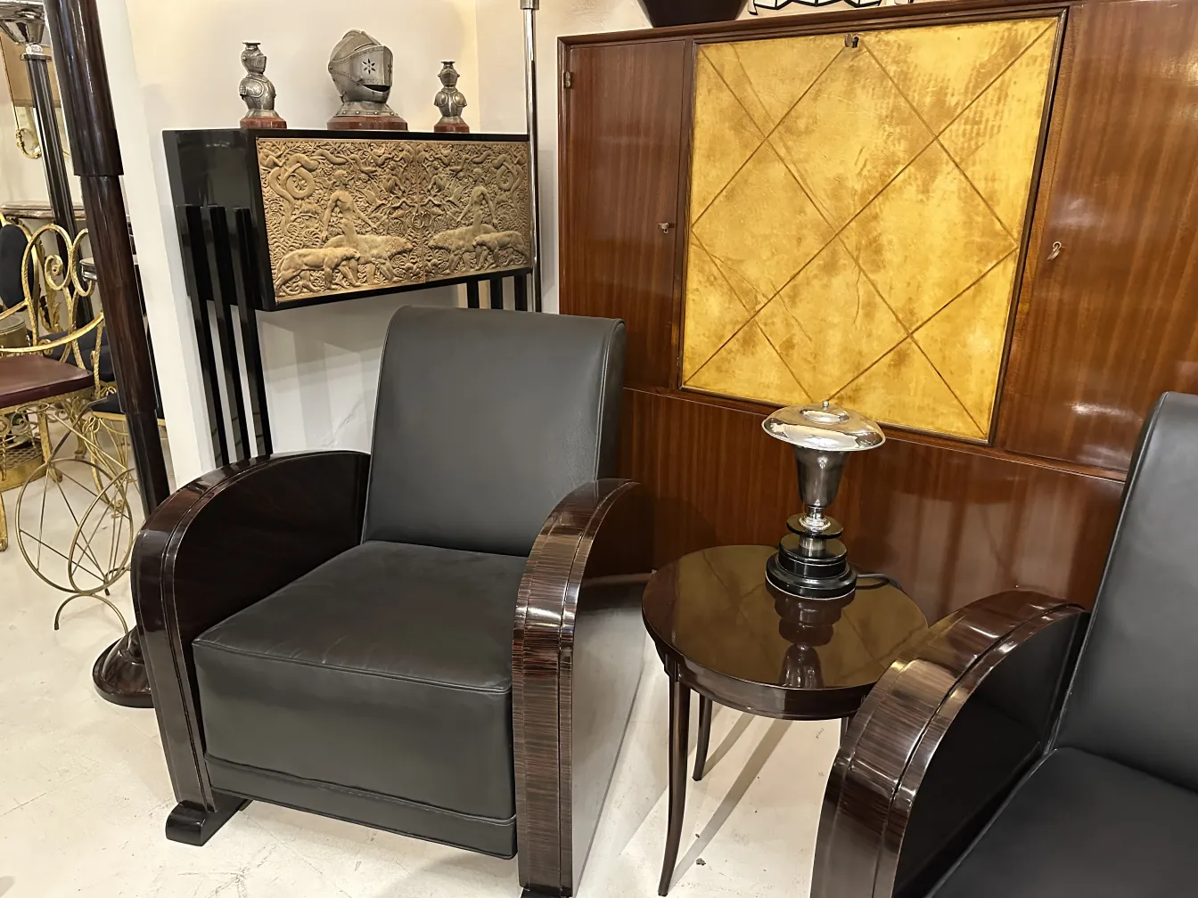 luminária de mesa antiga com base preta e detalhes ornados, ao lado de cadeiras