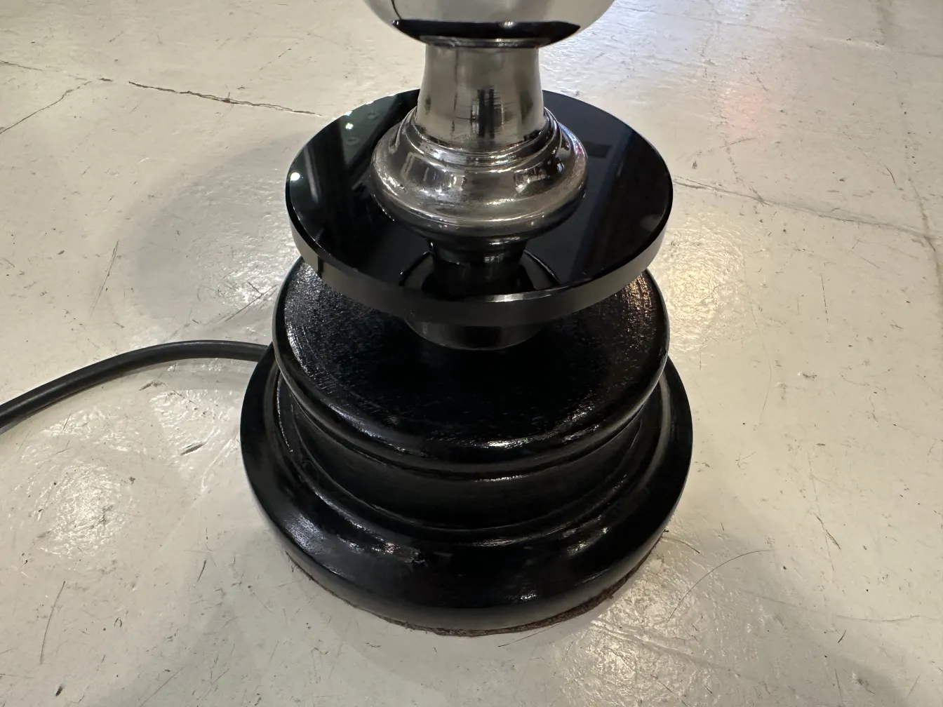 Lámpara de mesa antigua con base negra brillante en un ambiente sencillo.