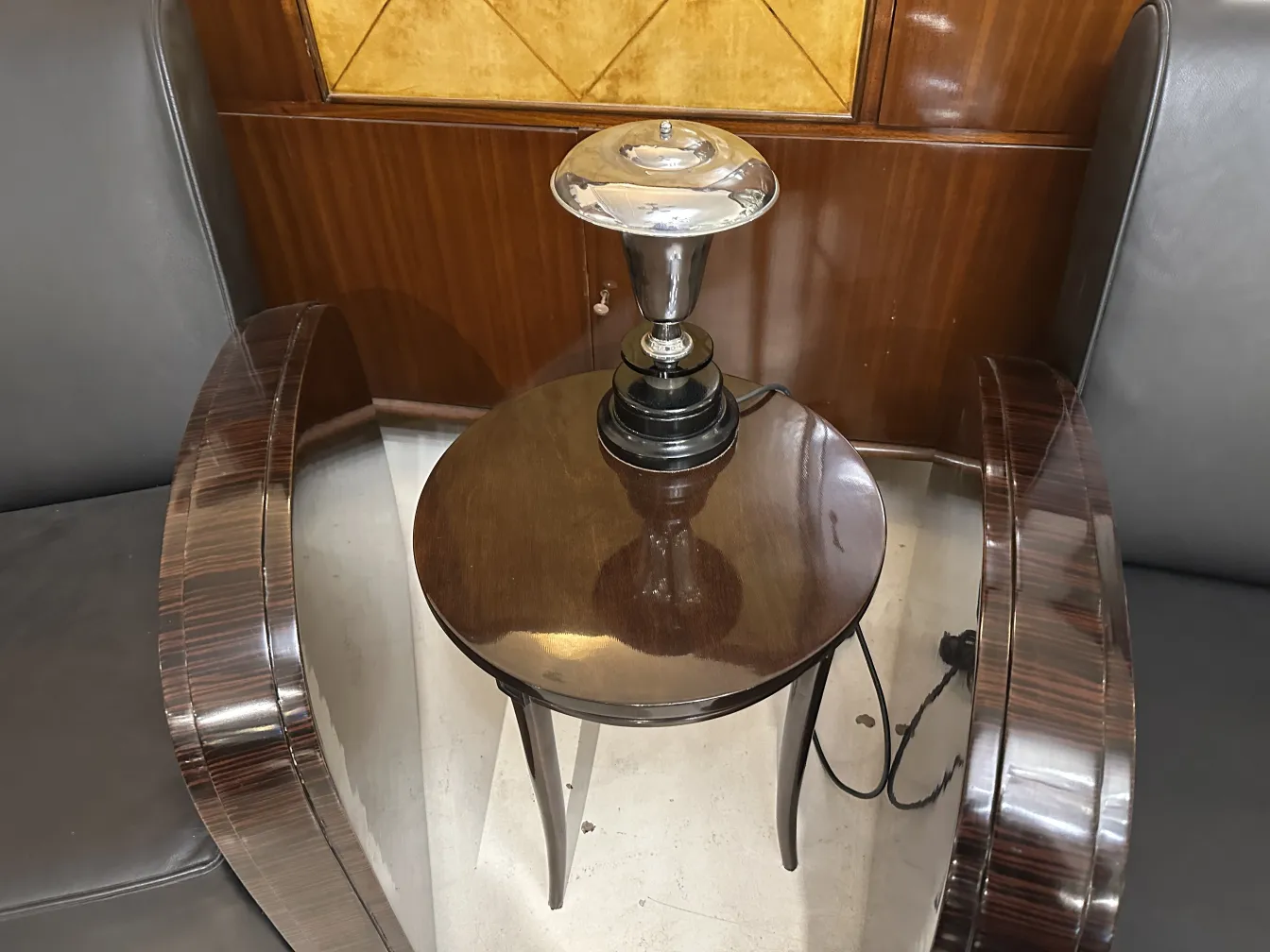 Antike Tischlampe mit klassischem Design auf einem kleinen Tisch in einer eleganten Umgebung.