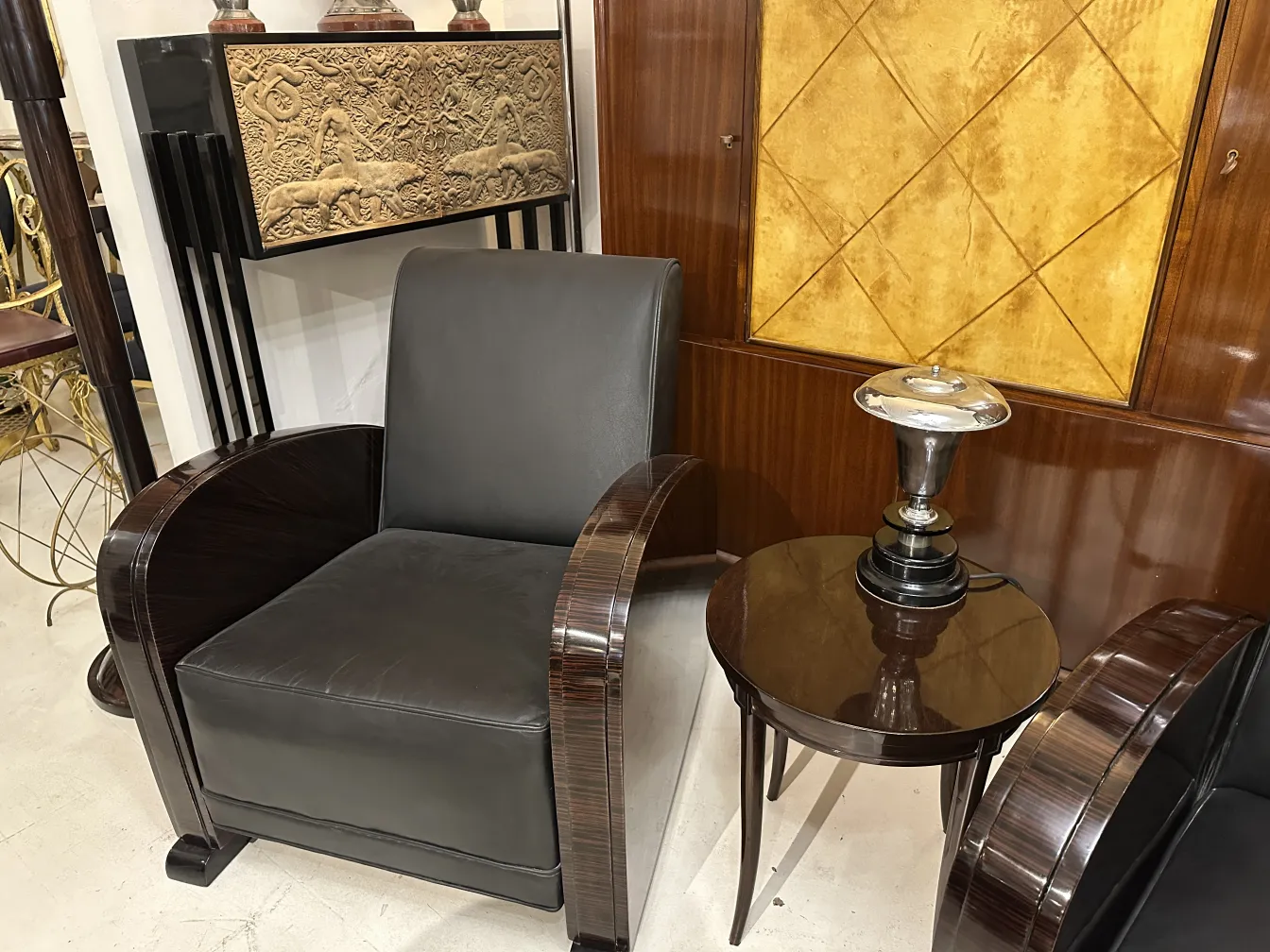 Antique table lamp on round table beside an armchair.