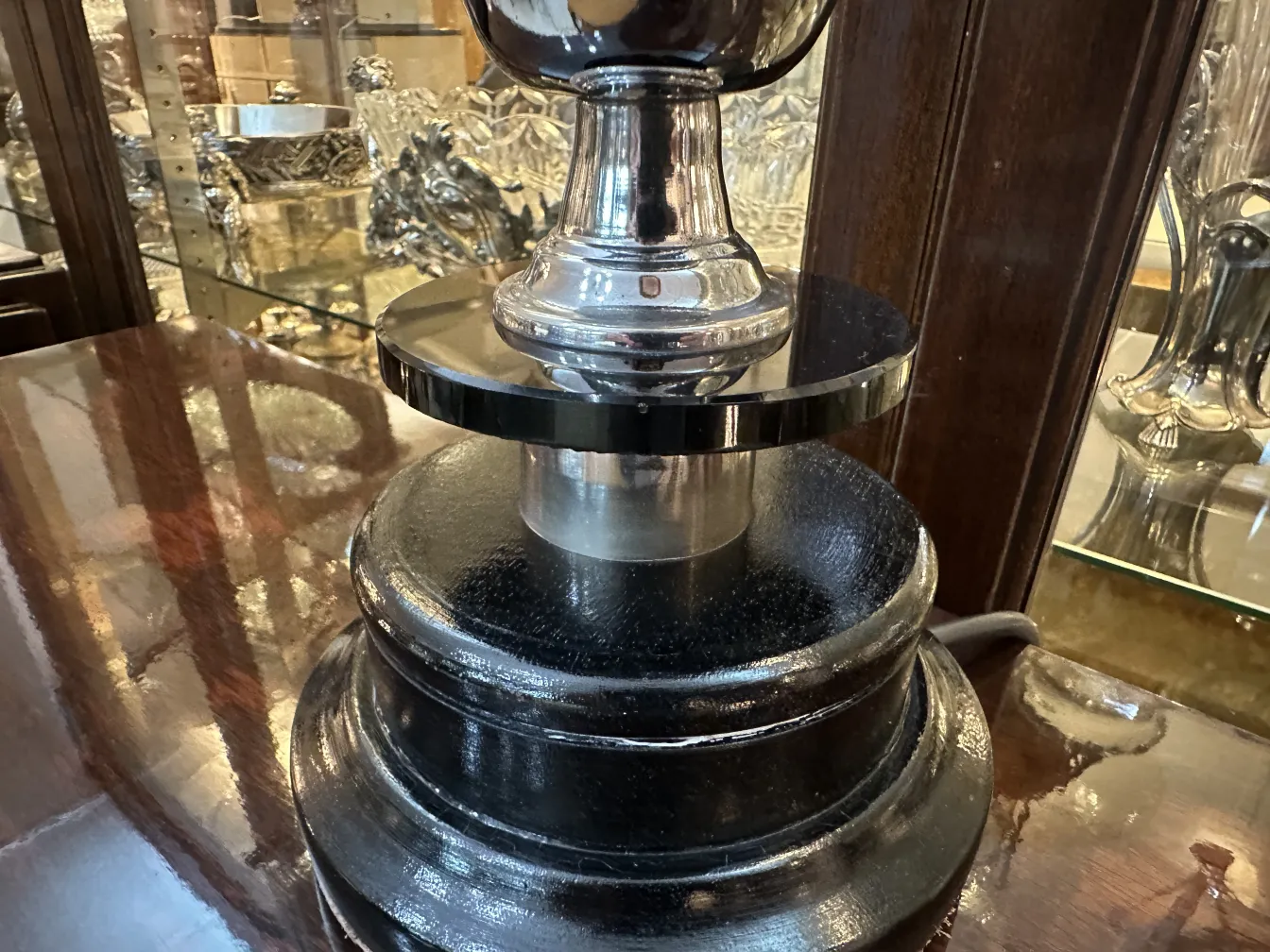 Lampe de bureau ancienne avec base noire et détails brillants dans un cadre élégant.