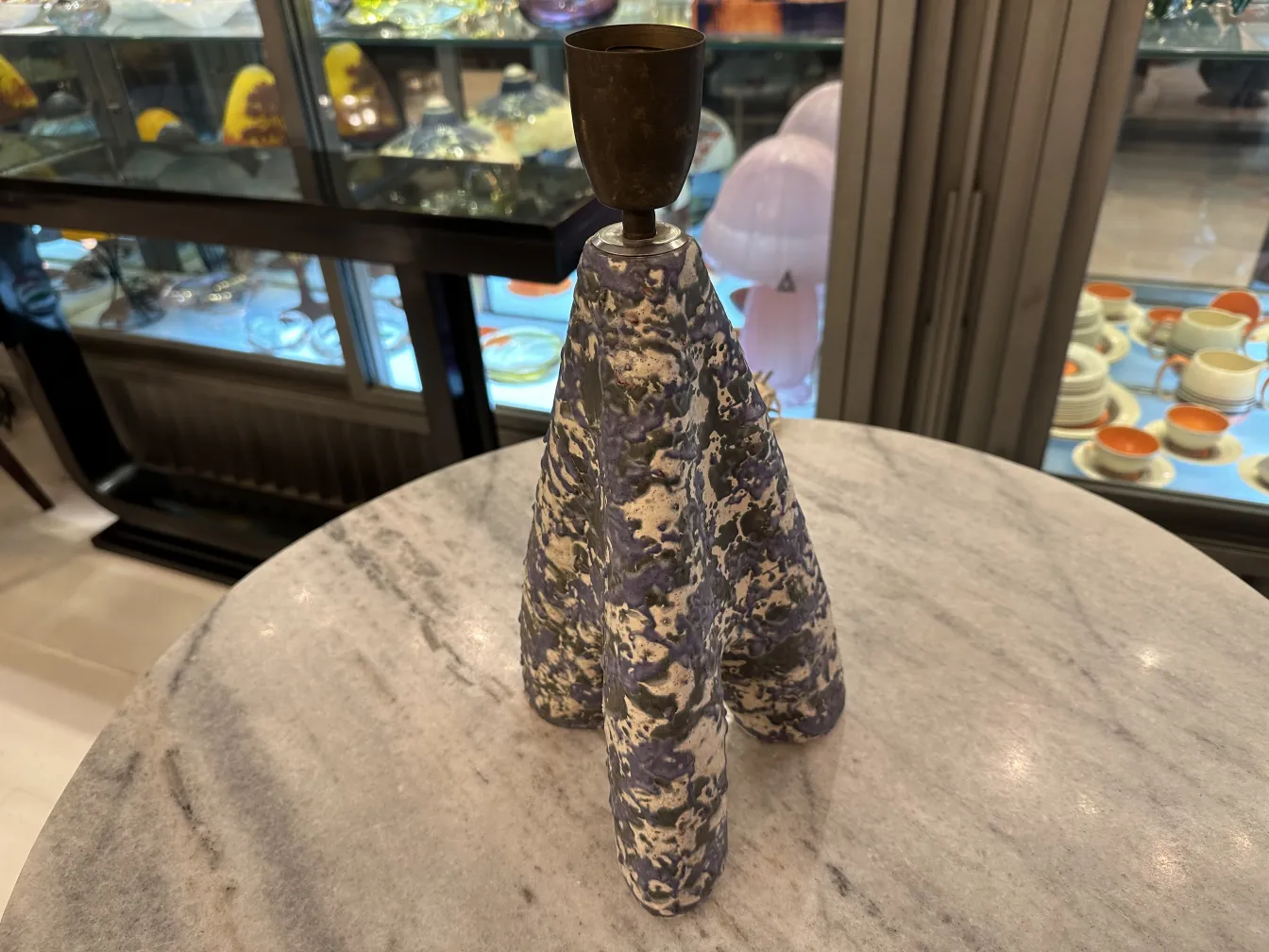 lámpara de mesa antigua con base decorativa en cerámica, en un ambiente elegante con objetos de vidrio al fondo