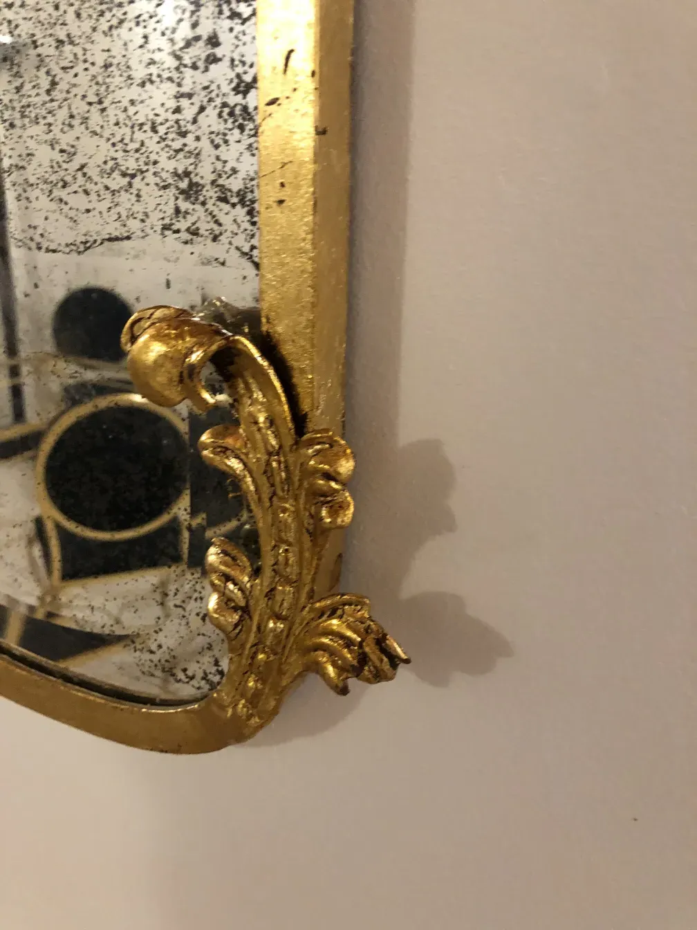 Espelho antigo decorado com elementos dourados.