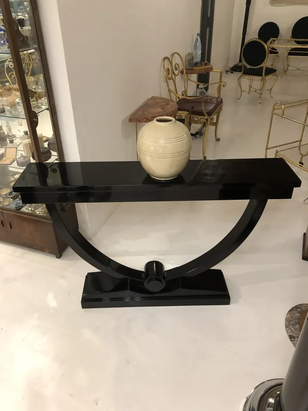 consola decorativa antiga preta com design curvo e vaso branco