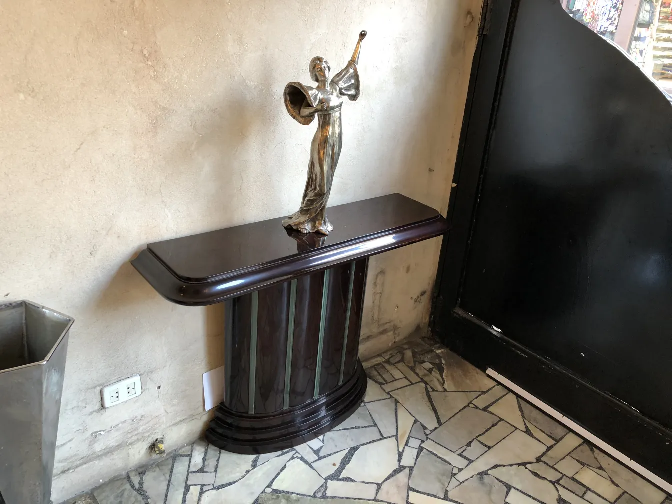 consola antigua con escultura decorativa y fondo neutro