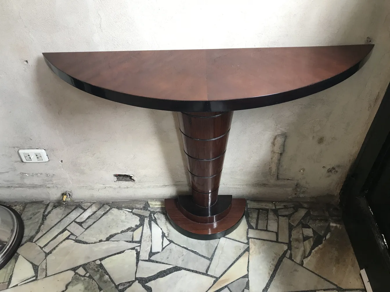 una consolle antica con forma semicircolare e base elegante in un ambiente neutro