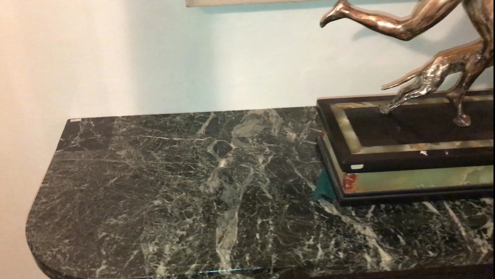 antiga consola decorativa com figura de metal em cima