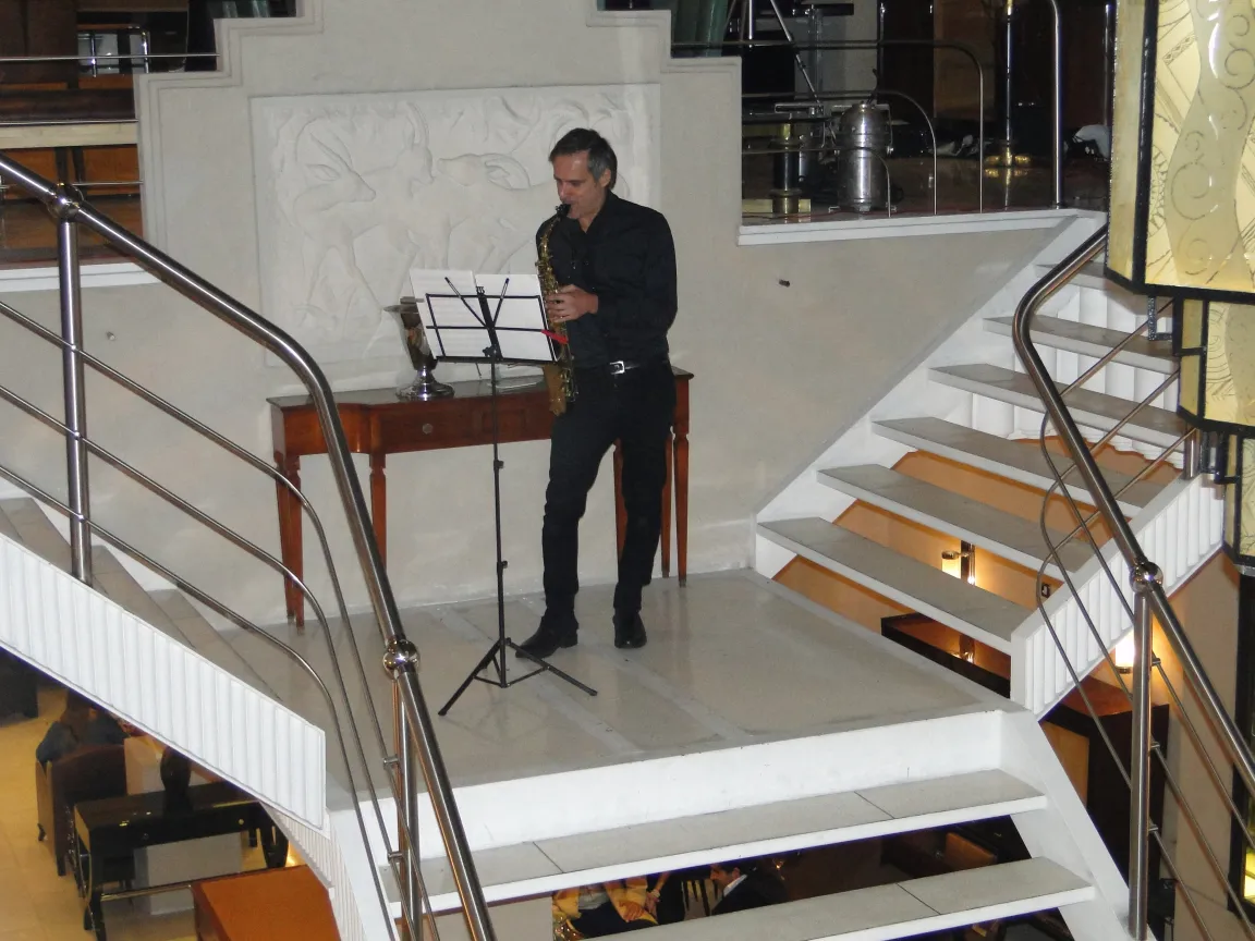 música suave tocada por um saxofonista em um ambiente elegante ao lado de uma antiga consola comte