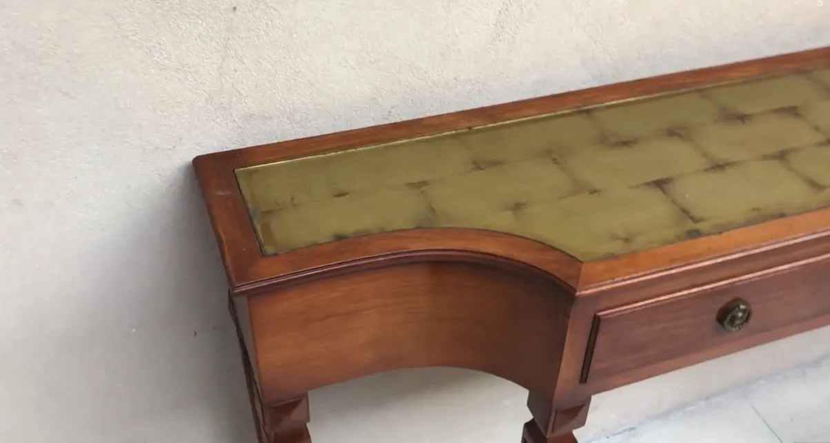 Ancien dresuar avec surface décorative et tiroir dans un cadre neutre.