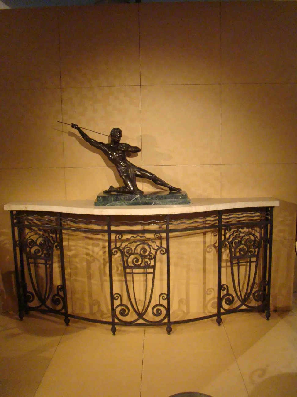 Consola antigua decorativa con escultura en el centro, fondo neutro.