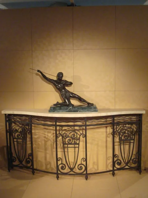 Antike Konsole mit Skulptur oben, vor einem schlichten Hintergrund.