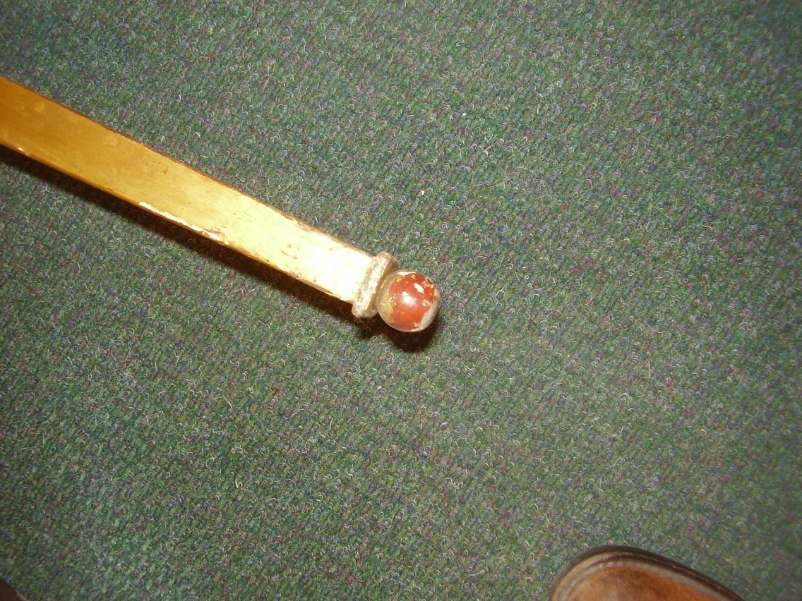 Détail d'une ancienne console décorative avec finition dorée et sphère.