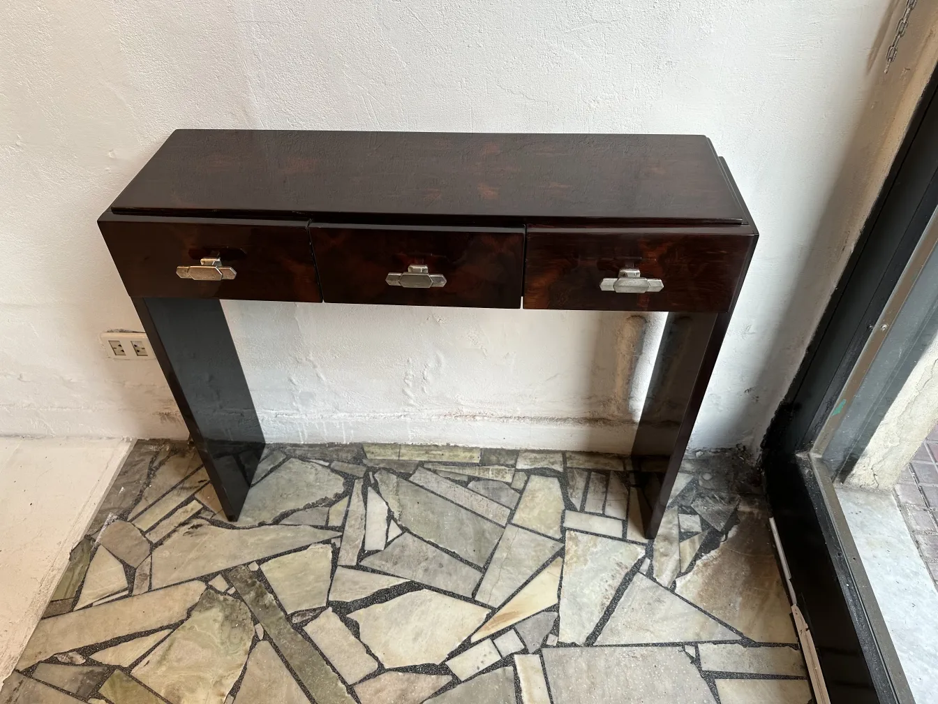 View of 2 antique consoles, each with three drawers, on a stone floor