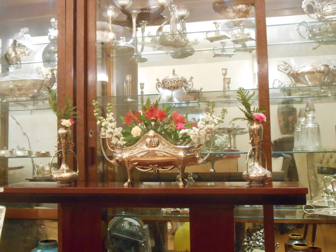 Três consoles antigas com flores decorativas e vasos