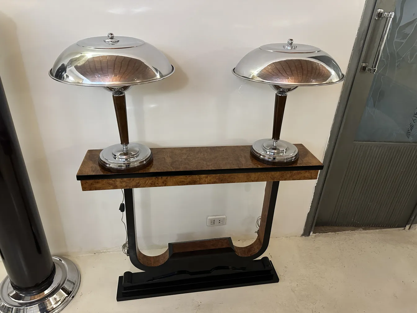 Três consolas antigas com lâmpadas prateadas em um ambiente elegante.