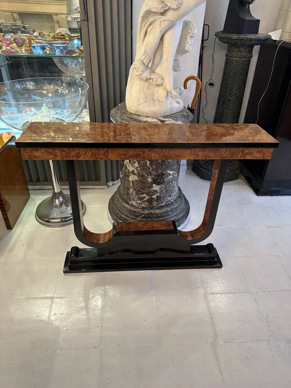 Três consoles antigos em um ambiente clássico com uma estátua e fundo iluminado