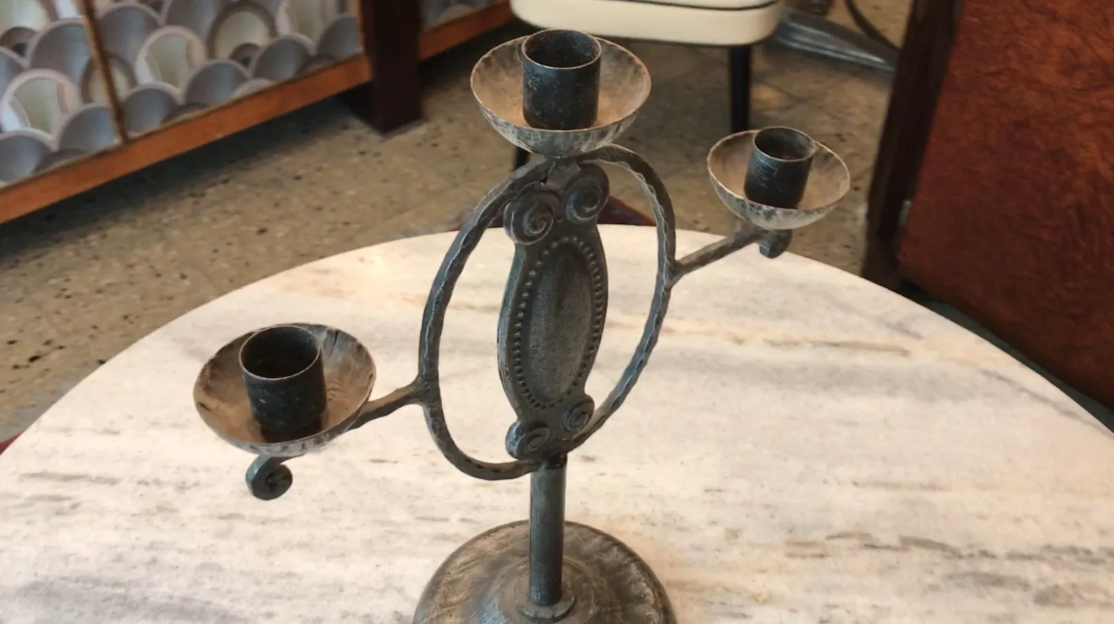 Candelabra purana teen brah aur sajawat base pe, table par rakha hua. Aaramdayak mahol.