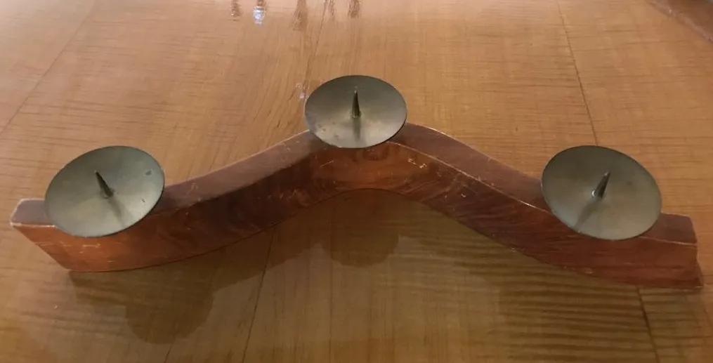 Candelabro antico con due porta-candele su una base curva su un tavolo di legno.