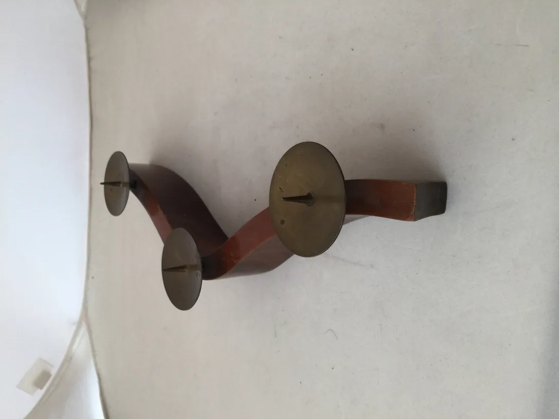 Candelabro antiguo de tres brazos con base curvada, en un ambiente neutro.