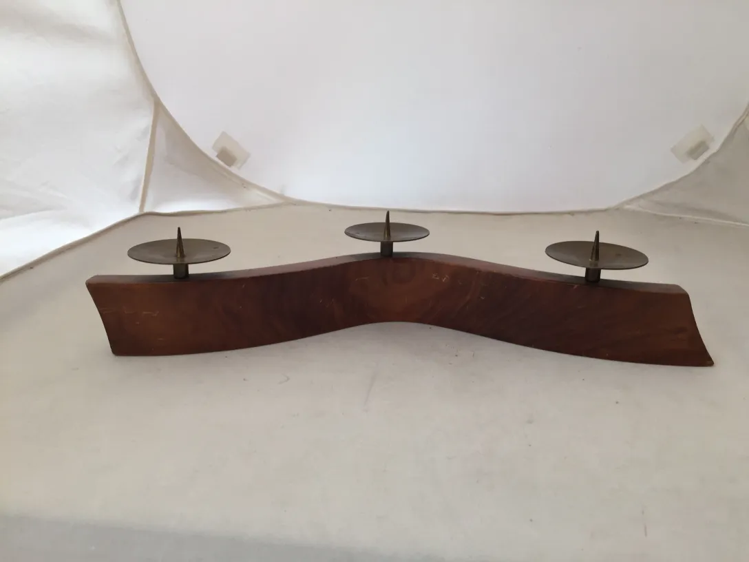 شمعدان قديم ذو شكل منحنٍ وقاعدتين للشمع على خلفية بيضاء.