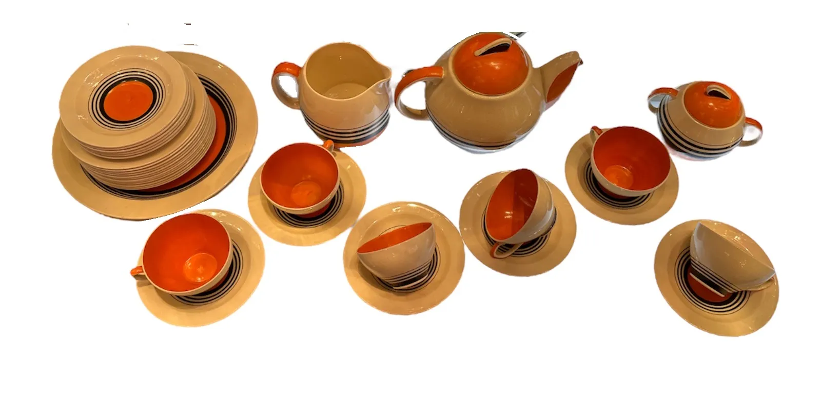 Antico set da tè con motivi colorati su tazze, piatti e teiera disposti in diverse posizioni, creando una collezione armoniosa.