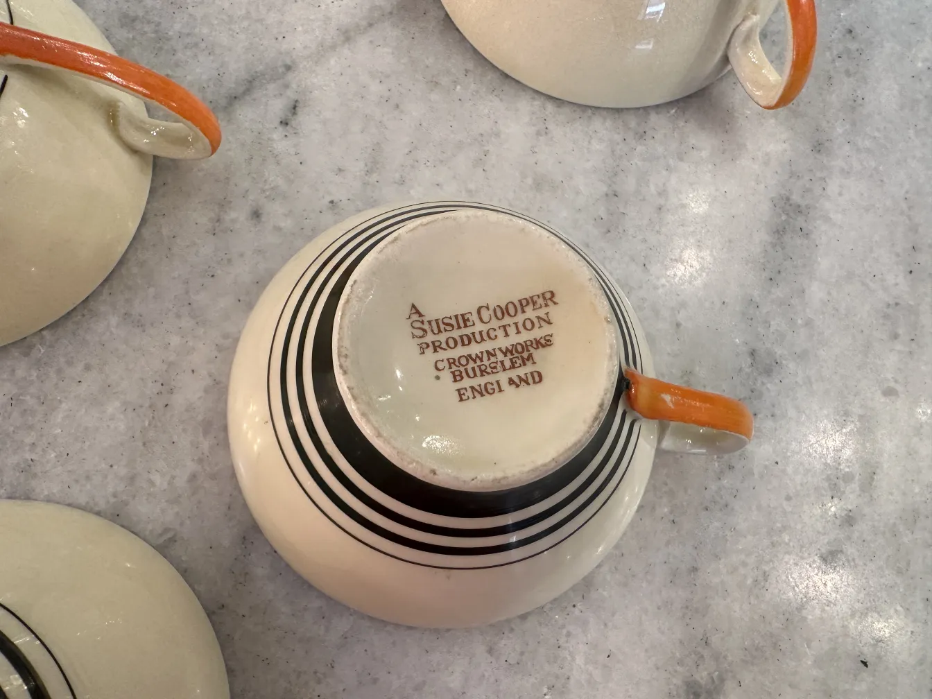 conjunto de chá antigo com xícara laranja e padrões em preto e branco em fundo claro