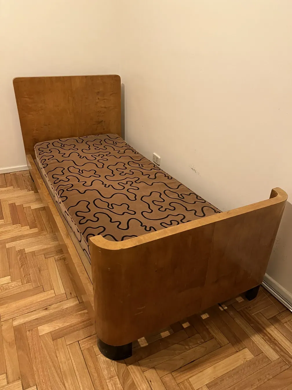 Cama antigua con diseño único y colchón estampado, entorno simple.