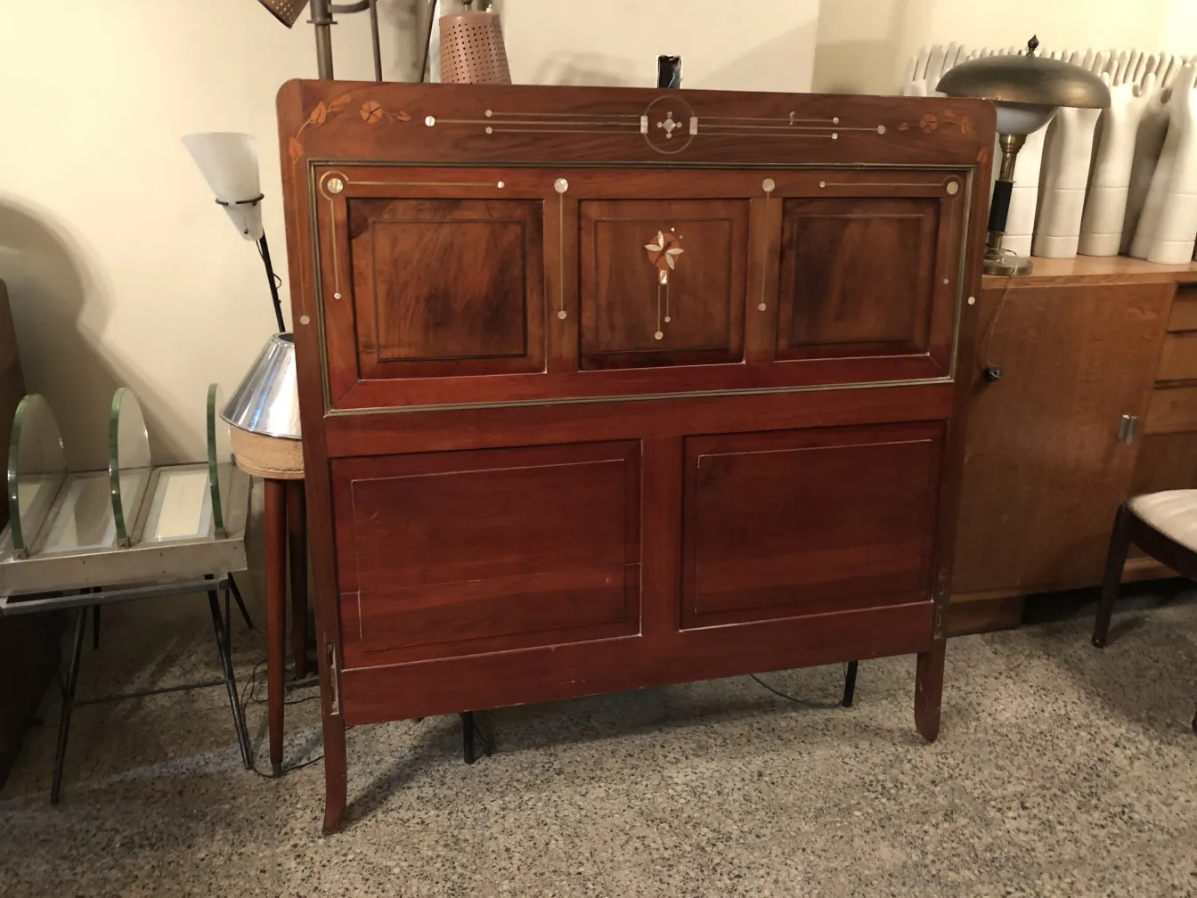 Lit ancien avec tête de lit décorée dans un cadre vintage.