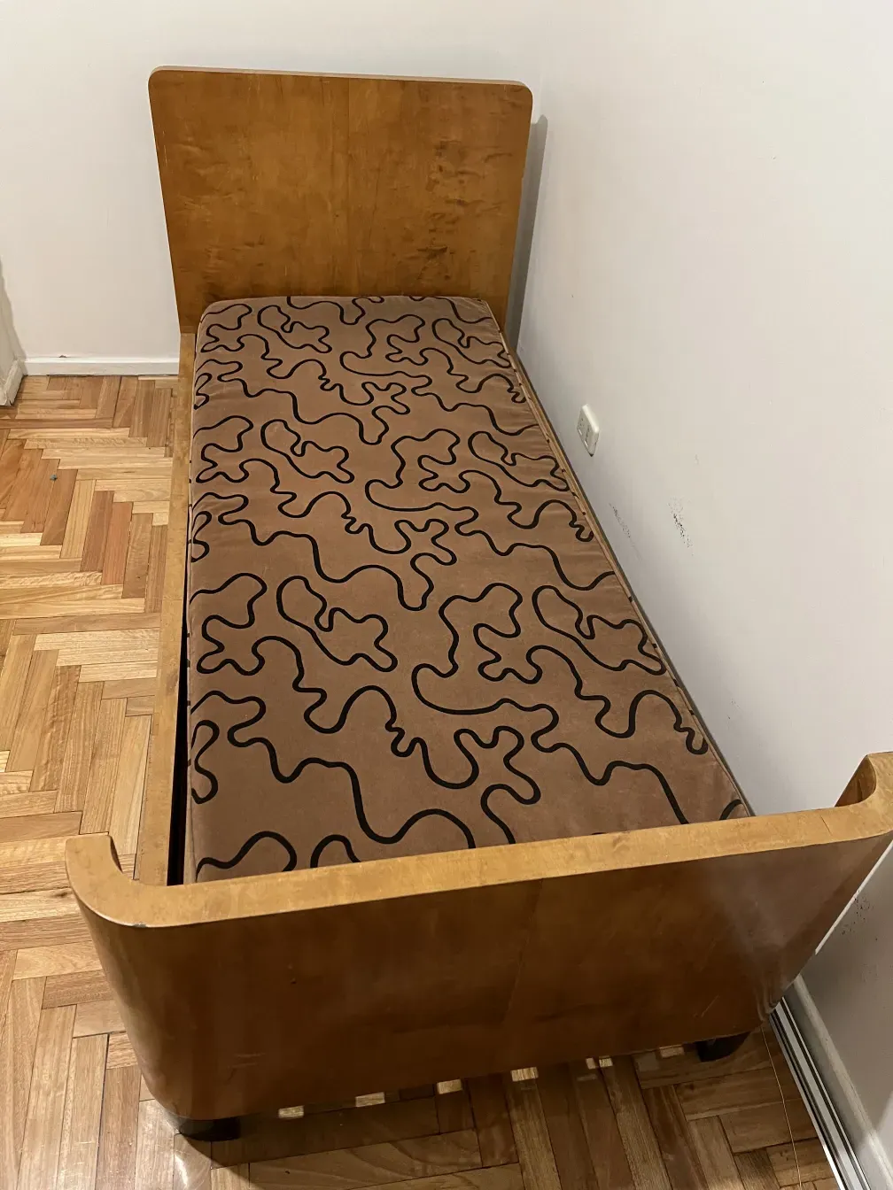 Lit ancien avec design géométrique et coussin dans une ambiance chaleureuse