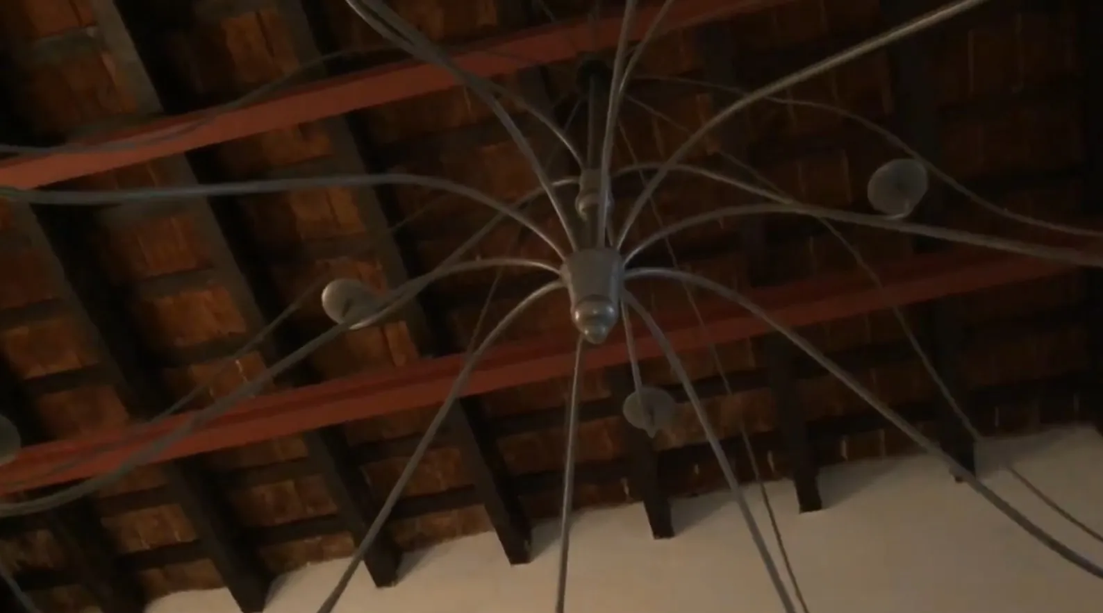 Tres lámparas de techo antiguas con brazos curvados en ambiente rústico