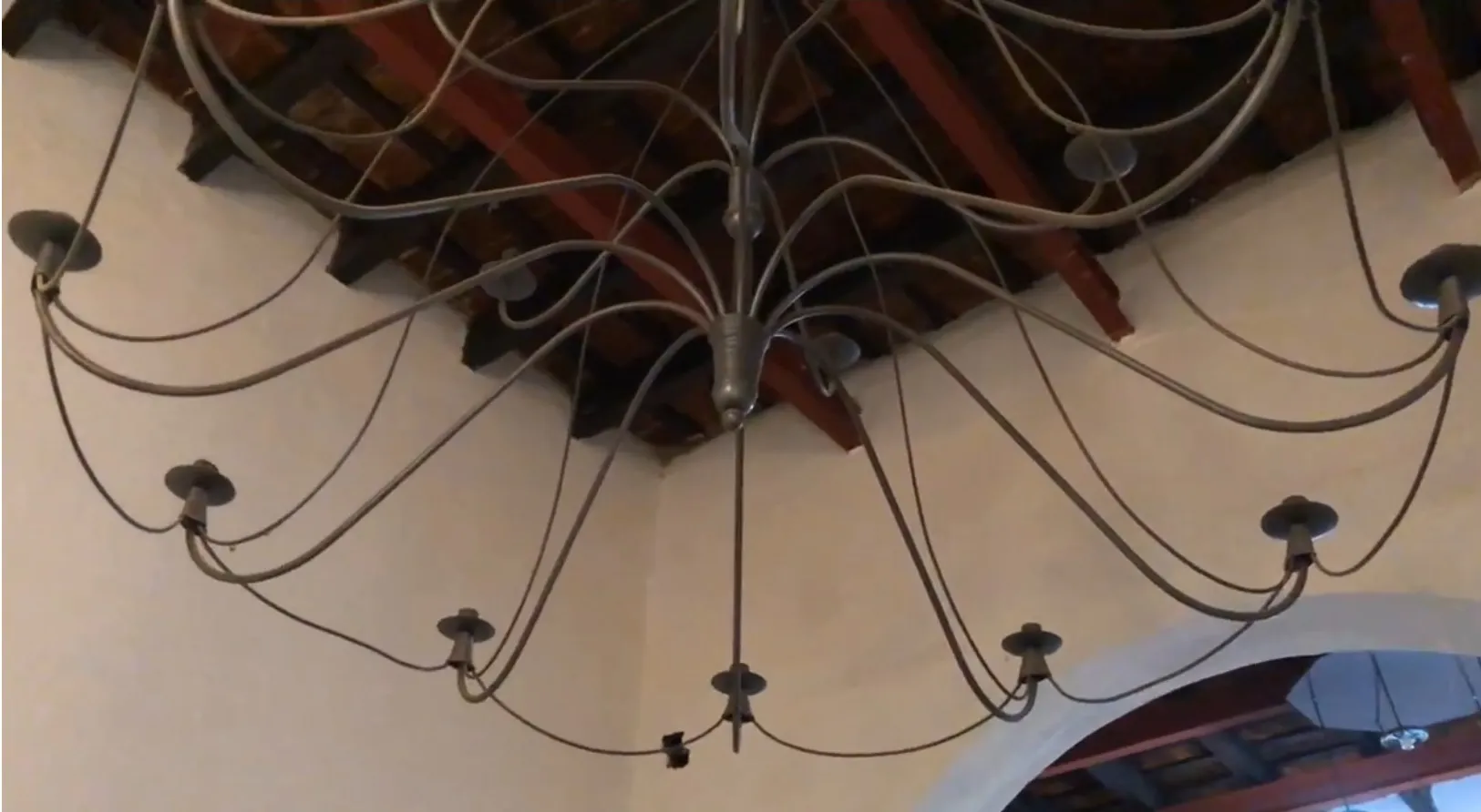 Tre lampade a sospensione antiche con braccia curve, design elegante.