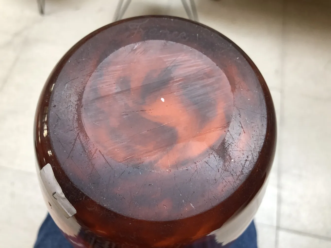 Verre signé Muller Freres, objet ancien avec des détails uniques, posé sur une surface neutre.