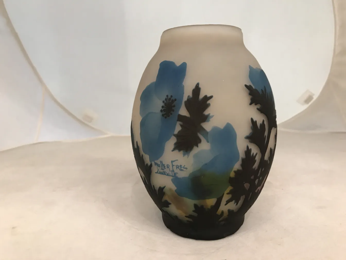 Vidrio firmado Muller Fres con decoraciones florales azules sobre fondo claro.