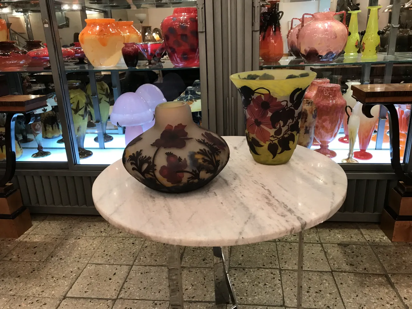 Signed glass by Muller Fres with colorful decoration on dark background over marble table.