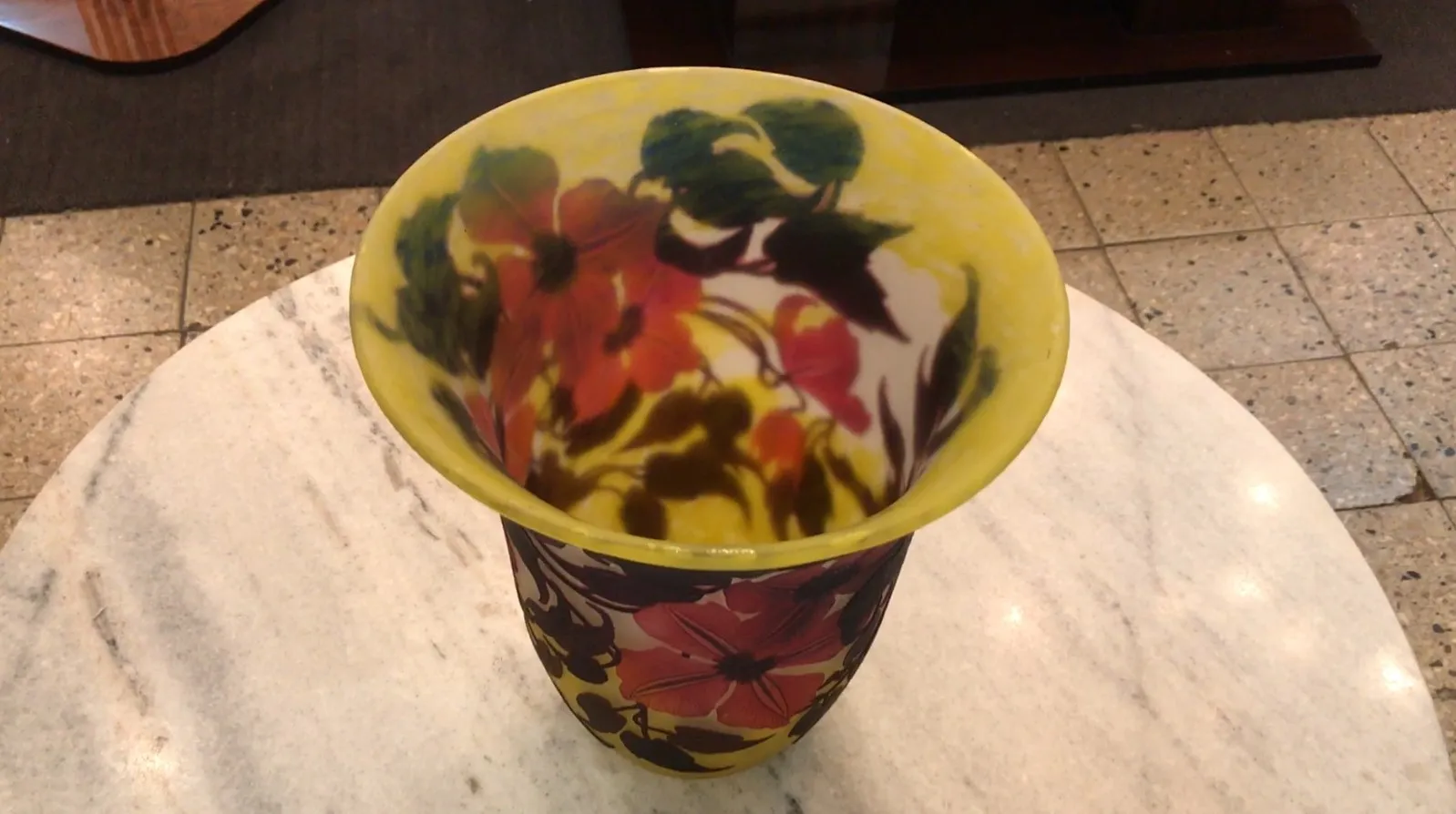 Vase ancien en verre signé Muller Fres avec des motifs floraux colorés sur un fond clair, posé sur une table en marbre.
