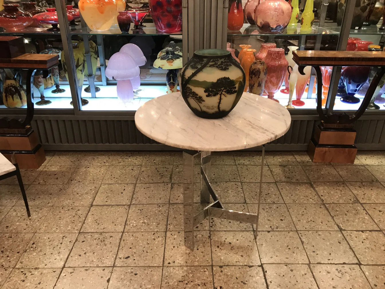 Verre signé de Muller Freres exposé sur une table avec d'autres antiquités.