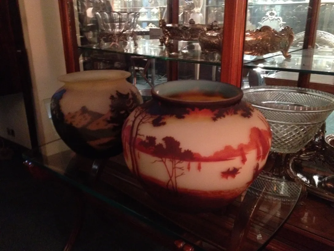 Duas jarras antigas decoradas com uma paisagem, ambiente de museu.