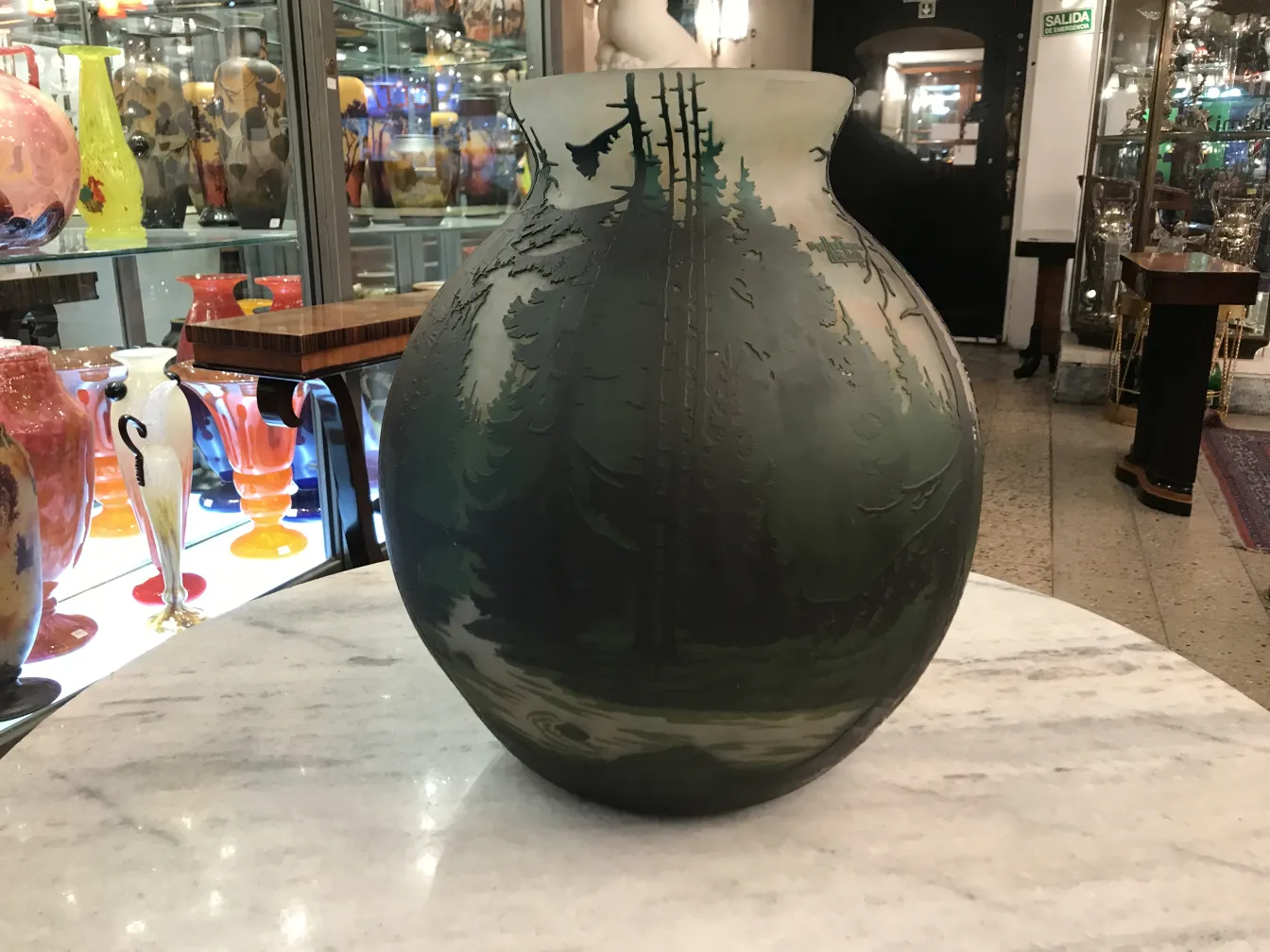 jarrón antiguo con detalles de bosque y vidrio firmado Muller Fres, rodeado de otros objetos decorativos